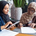 Young Muslim female private practice owners sitting in cafe, writing blog posts and using tablet for SEO on therapy websites. Simplified SEO Consulting can help your speech therapy website rank higher in search engines like Google and Bing!