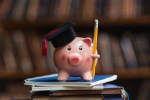 Image of a ceramic pig wearing a graduation cap standing on notebooks. This image represents the lack of knowledge therapists get about private practice SEO in grad school. Reach out for SEO help for therapists here.