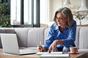 middle aged woman writes notes about optimizing her website after taking an online SEO course with Simplified SEO consulting to learn about SEO for online therapy. 