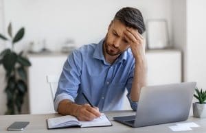 middle age man at his computer looks frustrated writing content for SEO. He gets tips on readability and writing content for his private practice from SEO specialist at Simplified SEO Consulting