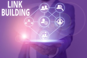 purple graphic for link building being held up by man holding tablet. SEO backlinking is a great way to increase credibility with Google. However this must be done with ethical seo strategies. Learn more about seo for mental health professionals today!