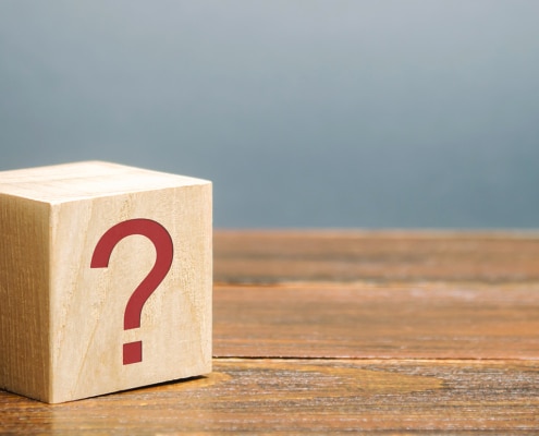 Image of a wooden block with a red question mark on its side. This image illustrates the many questions clients have about SEO, including "how long does SEO take?"