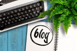 Typewriter and notebook with "blog" written with a small fern on a teal background. SEO tips for therapists can be found on this blog from SEO experts to hire for help or get resources from at Simplified SEO Consulting for private practice SEO.