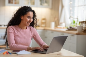 Woman in pink on laptop smiling. If you're wondering how video can improve your SEO strategy, you've come to the right place. Video and Seo can give you an additonal stream of people to your website with the right therapy keywords. Learn more about Youtube SEO today!