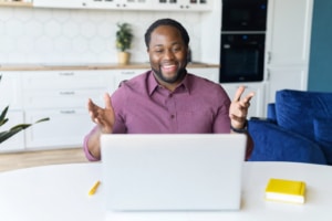Happy man at his computer smiles as he meets with a group of therapists for a 12-week SEO mastermind with Simplified SEO Consulting