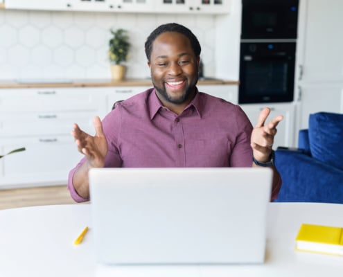 Happy man at his computer smiles as he meets with a group of therapists for a 12-week SEO mastermind with Simplified SEO Consulting