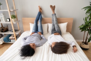 African american woman laying on bed facing each other with legs up on wall. Its time to invest in SEO for therapists and we are here to help. Begin learning more marketing strategies for African Americans and the black community today!