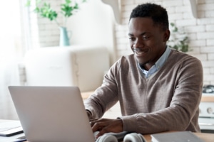 Happy man types on his laptop representing the joy that can come from writing what you want when you blog for SEO. Learn more from an seo specialist and copywriter at Simplified SEO Consulting 