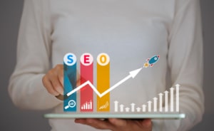 A person points to a graphic with the text SEO and a rocket above a graph. Learn how EAT seo can improve your rankings today. 