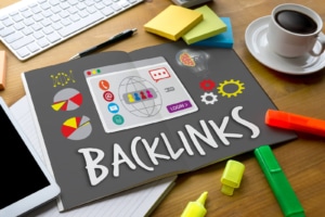 A picture of a poster board with the word "Backlinks" on a desk surrounded by markers, coffee, and a keyboard. This represents how you can use backlinks in your call to action and throughout your blog to let Google know that you own your therapy page, are a therapist, and know about the topic in your blog. Plus, it boosts your SEO. Learn more about backlinks today.