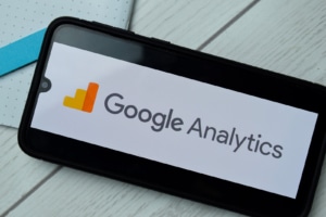 A close up of a phone with the logo for google analytics. Simplified SEO Consulting can offer support with Google Analytics for personal injury lawyers. Contact us today to learn more SEO techniques for law firms. 