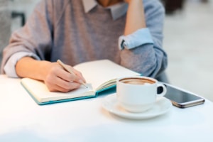 Image of a professional woman writing in a notebook. Identifying ideal clients is an important first step in SEO for psychiatrists in private practice. That list of ideal clients helps build quality SEO for mental health professionals Call today to speak with a SEO services consultant about what to do after identifying your ideal client.