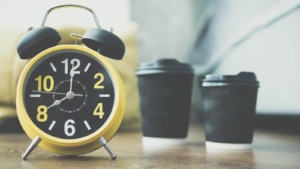 Yellow and black clock on table with black coffee cups. If you need support, but feel like you're running out of time, read this blog on SEO for counselors and why short term solutions don't work. We offer SEO for therapists, psychologists, and more!