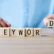 Photo of a man putting the word keyword together with lettered blocks. This photo represents the importance of using SEO keywords for personal injury lawyers to rank higher on Google. Contact us today to learn more.