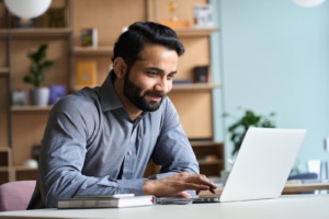 Image of a man smiling while typing on a computer. How to build SEO for therapists? Including and about the author will help with good SEO for therapists. Contact us today to see how we can help you with SEO for private practices. Reach out now!
