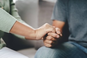 A picture of two people sitting and holding hands for comfort. This represents how the call to action on your therapy pages on your private practice website can show potential clients that you are here to comfort and support them. Learn more about writing a call to action to build SEO for therapists and improving your private practice website today.