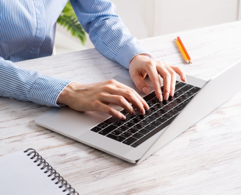 Shows a therapist typing a blog on their laptop. Represents how therapists show write their own blogs to avoid duplicate content in pre-written therapist content.