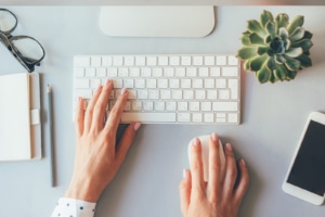 photo of a keyboard with a succulent, glasses and a phone. Light colors representing the calmness that can come from having a plan for your content marketing & SEO.