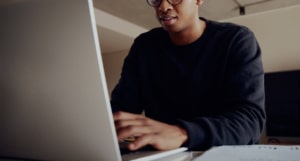 Photo of an African American man using his laptop to work on his website and improve his SEO. Learn how seo coaching can help you improve your website rankings.
