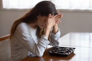Woman with chocolates on table and hands in head distressed. Sometimes we struggle to manage food and body on our own. An eating disorder therapist in Atlanta, GA who offers eating disorder therapy, anorexia treatment, and bulimia treatment can help. Call now and book a free consultation.