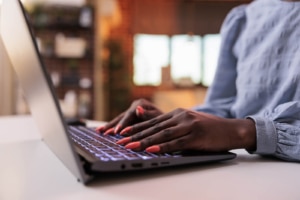 Photo from Bigstock of an African American female's hands on a computer representing a private practice owner who wants their psychiatry practice to rank well on Google and improve their SEO without blogging.