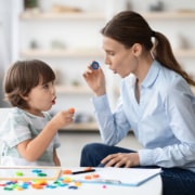 Photo of a speech pathologist working with a young boy on articulation. This represents a pediatric SLP with a full private practice able to see the clients she works most effectively with.