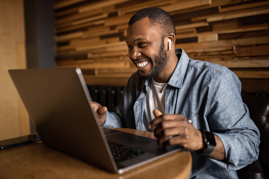 Photo of an African American man smiling while working on his laptop. Learn tips to improve your rankings and how you can get your practice ranking in the Google 3-pack.