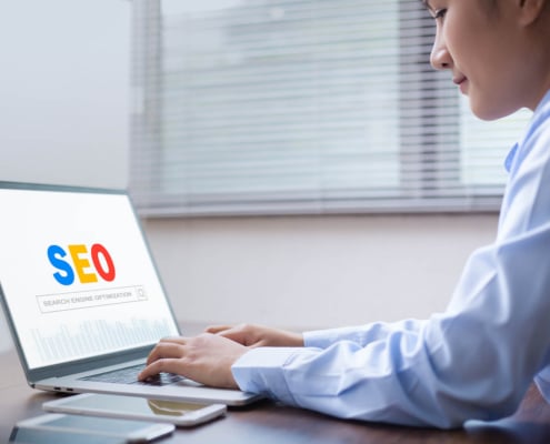 Photo of an Asian American woman using her laptop to improve her law firm SEO. Representing how improving your website's SEO can help you improve your online presence.