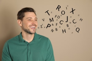 Man who looks like he's speaking with random letters coming our representing an adult with a speech or communication disorder requiring speech therapy.