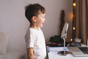 Photo of small boy looking at mirror representing a boy who's pediatric speech therapist has done excellent keyword research and used both long tail keywords and short tail keywords as part of their overall SEO strategy.