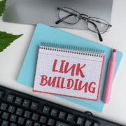 A top down view of a notebook in front of a laptop that reads “link building”. Learn how to build links to improve SEO for therapists by building backlinks for therapists. Find a guide to earning backlinks to learn more today.