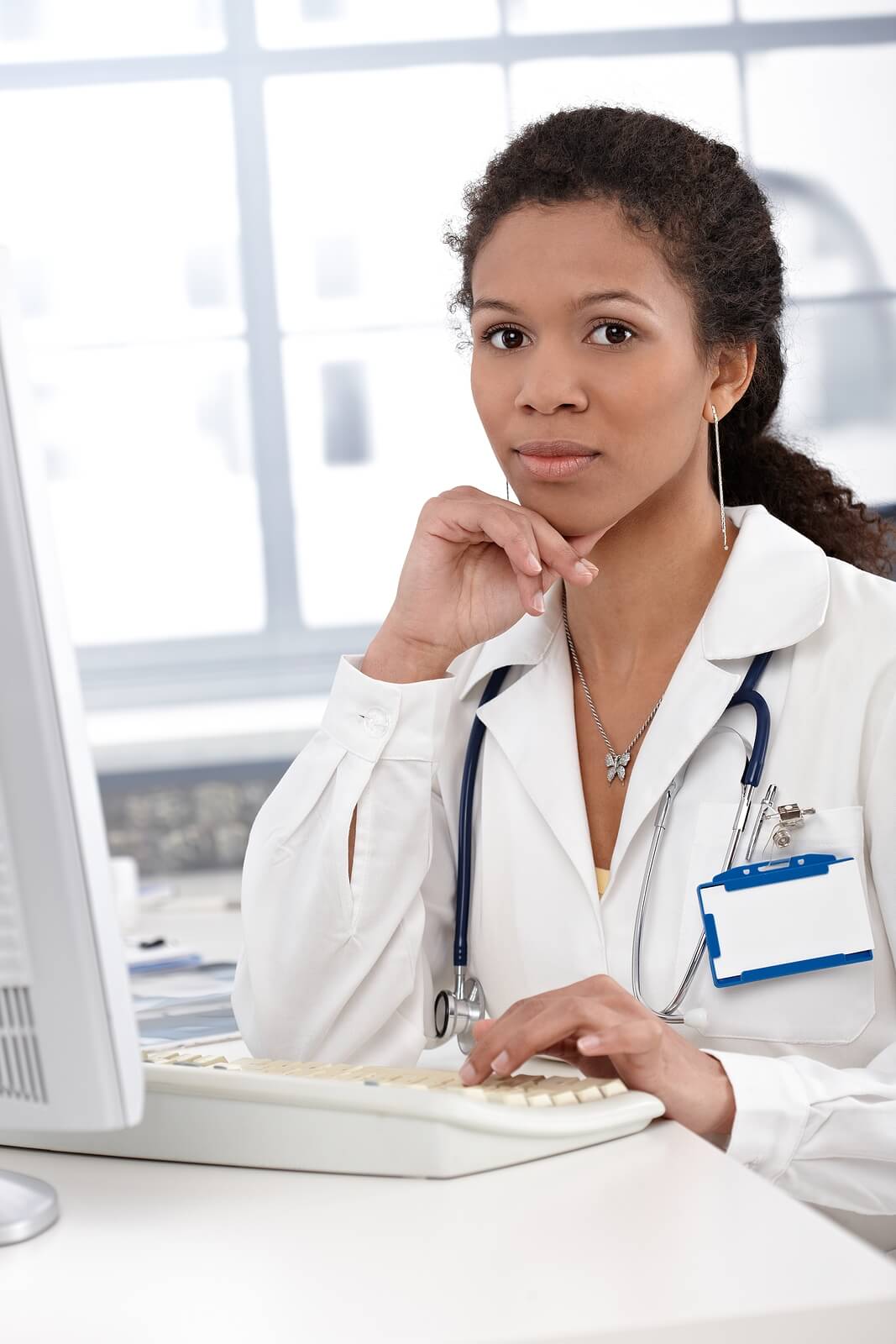 A woman doctor sits at a computer. Looking to learn more about SEO as a functional medicine doctor? Our SEO services can help your practice today!