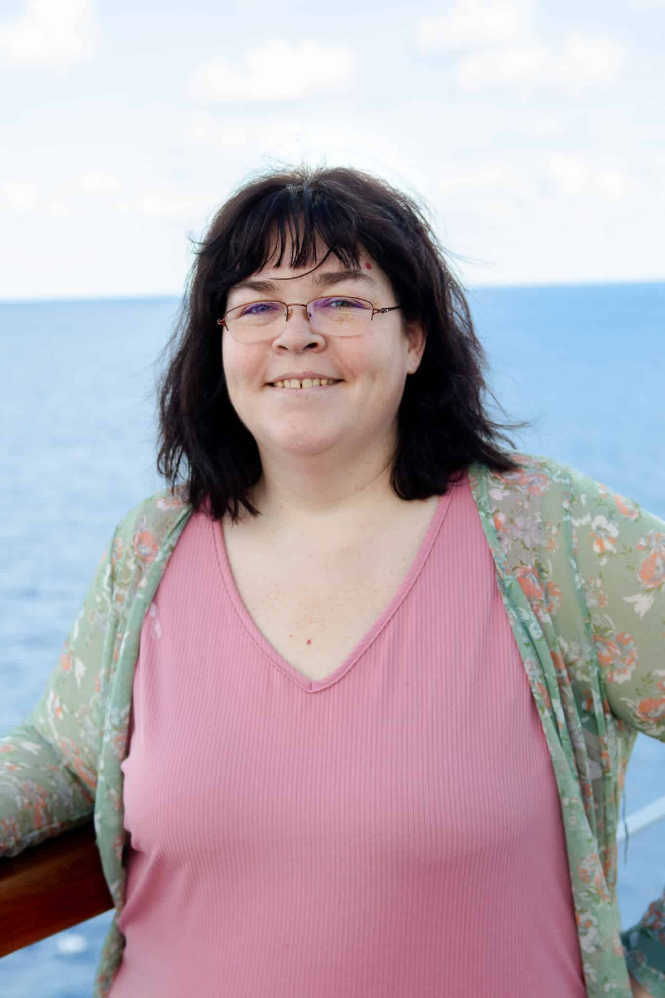 Mary, Mental Health SEO Specialist, outside over the ocean smiling. Mary is a technical SEO Specialist for mental health counseling and therapy websites in the United States, United Kingdom, Canada, and beyond.