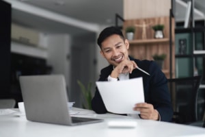 Photo of a smiling Asian man holding a piece of paper and smiling. Learn what readability is and how you can edit your content to help with readability. Begin working to help your private practice SEO. 