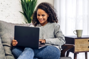 Shows a woman smiling at a computer. Represents how therapist seo can be more client focused with SEO and storybrand.