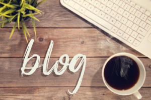 A cup of coffee, a keyboard and "blog". Blogging is beneficial for Personal Injury SEO. Discover different SEO techniques!