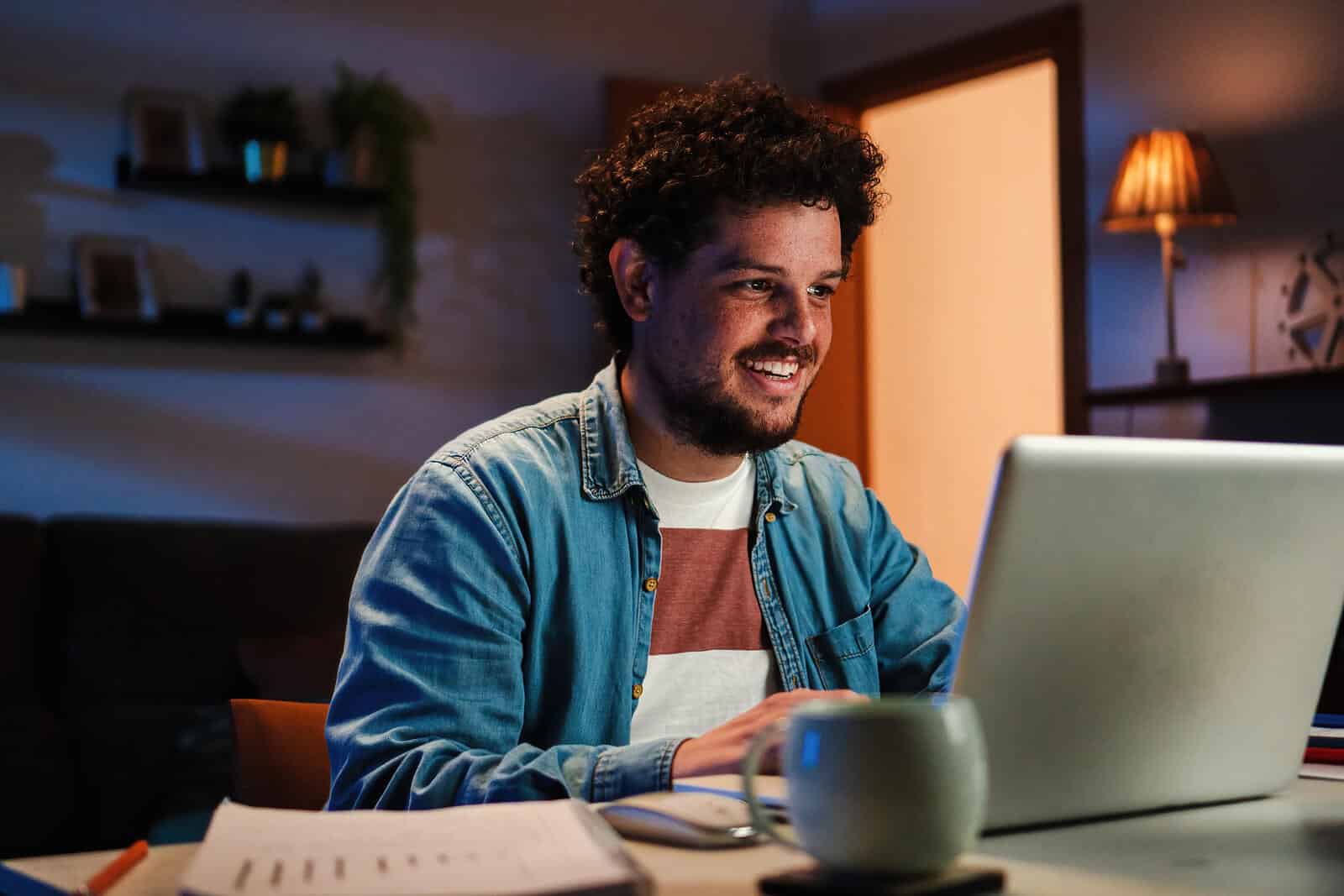 Image of a man sitting at a laptop working and smiling. Learn what SEO is and how effective it can be to boost your rankings on search engines.