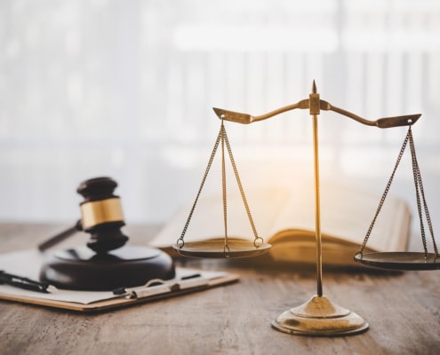 A wooden mallet & scale of justice on table. There are multiple benefits in using SEO for law firms. Discover what keywords you should use here.