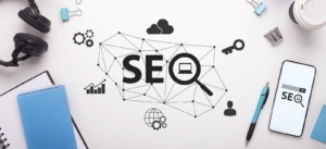 A top down view of the word SEO on a desk surrounded by different SEO elements. Learn tips for improving backlinks for therapists by searching for a guide to earning backlinks today