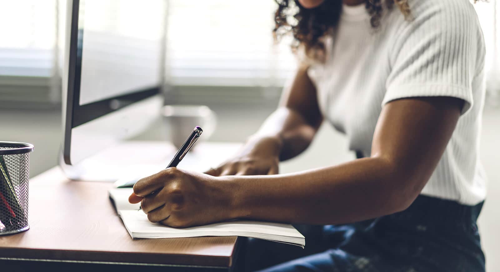 A woman sits at a desk while writing on a notebook. Wondering how DIY SEO can be implemented by you? Speak with an SEO specialist to learn how we can help you and your small business.