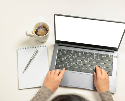 A person types on a laptop with notebook and coffee cup next to laptop. Looking for ways to implement SEO on your own? Speak with an SEO specialist to see how you can master DIY SEO for your small business.
