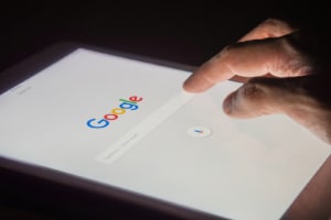A man's hand is touching screen on tablet at night for searching on Google. Learn more about keyword research tools for therapists and how they can offer SEO help for therapists. Find new SEO keywords for therapists 