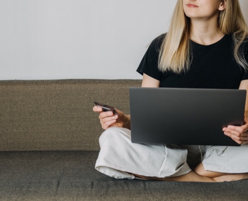 A close up of a woman holding a credit card while on a laptop. This could represent the pros and cons of paid SEO. Learn how to do SEO for therapists for free.