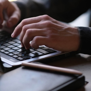Shows a man's hand typing on his laptop for private seo training. Represents how therapist SEO can be enhanced with writing targeted content.