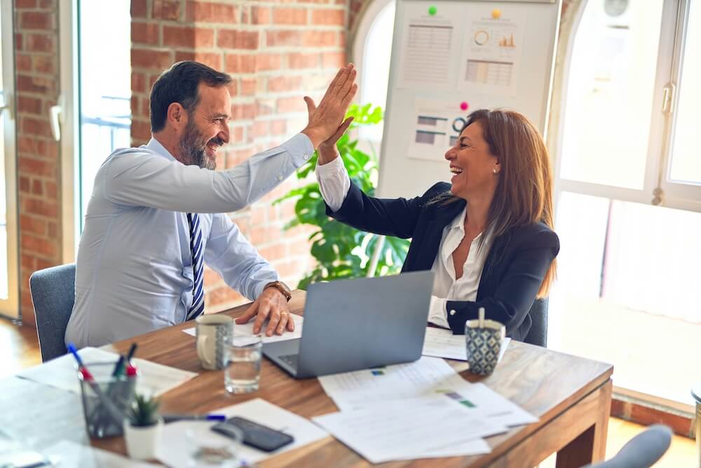 Image of a professional business man and woman smiling in high-fiving. Discover how to enhance your websites, visibility and search engines by utilizing Google search console.