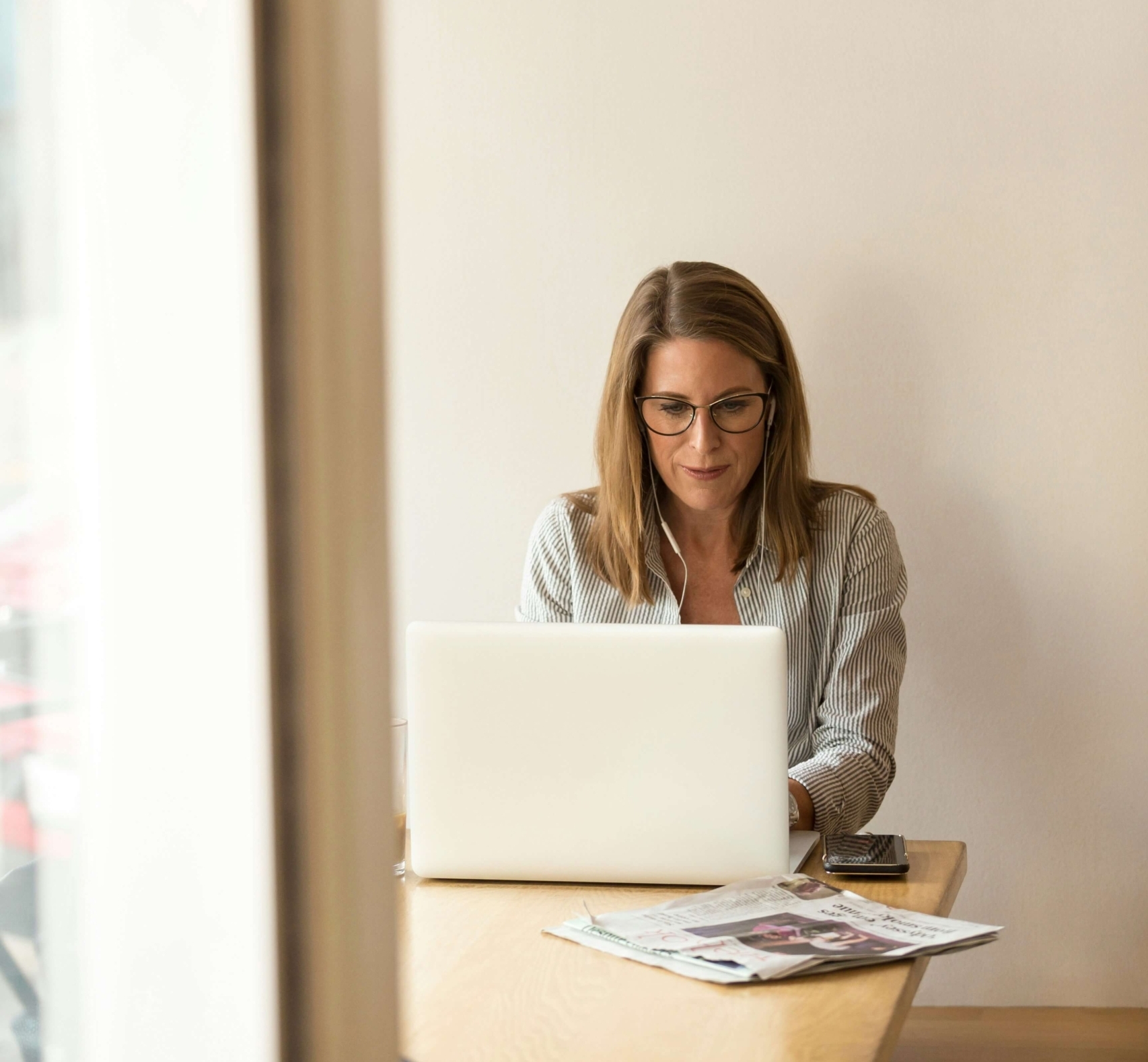 Image of a professional woman sitting at a table using a laptop. Discover how Google Search Console can help you uncover your website data and use it to find ideal clients for your private practice.