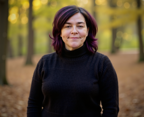 Mary Walker, owner of Simplified SEO Consulting stand in a tree lined area as leaves litter the ground.