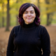 Mary Walker, owner of Simplified SEO Consulting stand in a tree lined area as leaves litter the ground.
