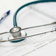 Stethoscope and medical documents on a desk, symbolizing the balance of clinical excellence and digital strategy through doctor SEO consulting.