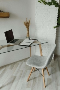 A glass desk & grey chair by a white wall, with a notebook open. Should doctors use SEO or social media marketing? Learn which is better in our blog!